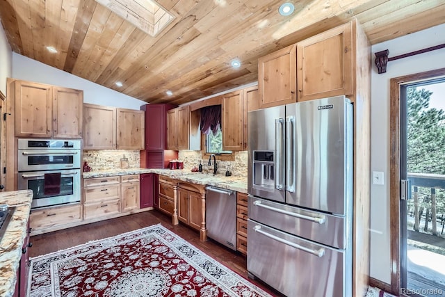 kitchen with vaulted ceiling with skylight, a sink, appliances with stainless steel finishes, a wealth of natural light, and decorative backsplash