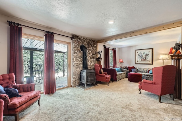 living area featuring a wood stove, carpet, a textured ceiling, and beamed ceiling