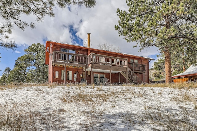 rear view of property featuring a wooden deck and stairs