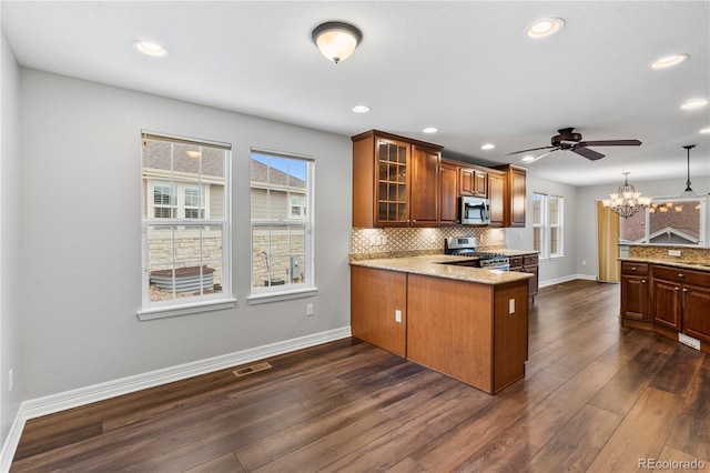 kitchen with appliances with stainless steel finishes, baseboards, a peninsula, glass insert cabinets, and tasteful backsplash