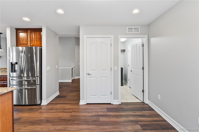 kitchen featuring stainless steel refrigerator with ice dispenser, light stone countertops, dark wood-style flooring, recessed lighting, and baseboards