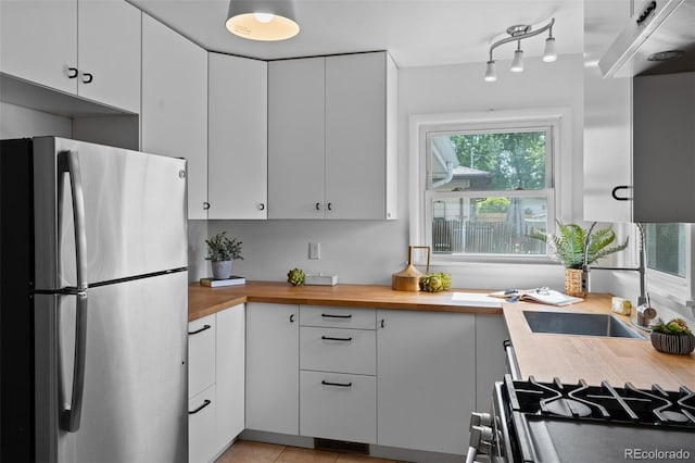 6755 W 45th Ave, Wheat Ridge, CO 80033 - kitchen featuring freestanding refrigerator, butcher block countertops, white cabinetry, light tile patterned floors, and gas range oven