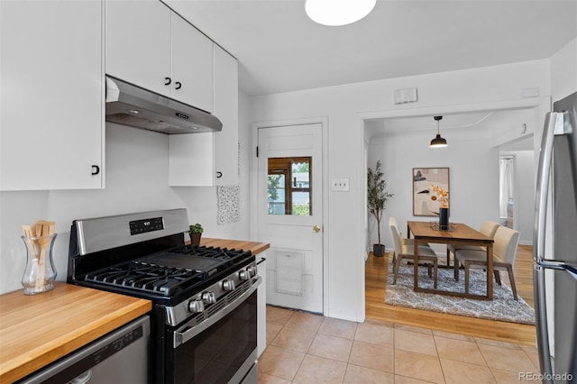 6755 W 45th Ave, Wheat Ridge, CO 80033 - kitchen with stainless steel appliances, under cabinet range hood, light tile patterned flooring, white cabinets, and hanging light fixtures
