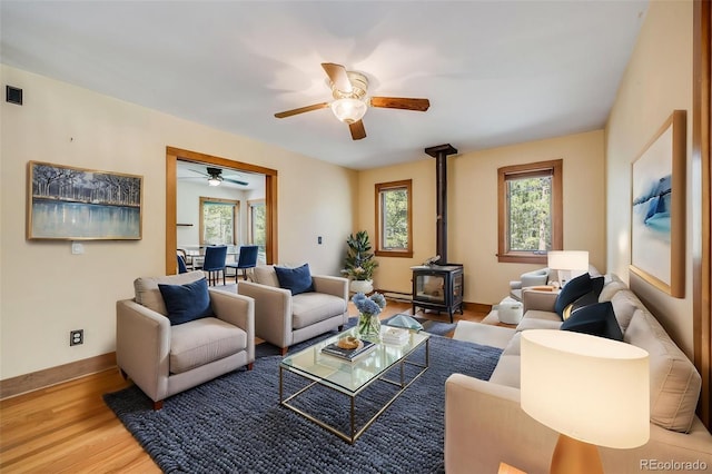 18247 State Highway 7, Lyons, CO 80540 - living room featuring a wood stove, healthy amount of natural light, a ceiling fan, and wood finished floors