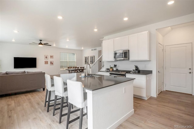 14818 Dahlia St, Thornton, CO 80602 - kitchen featuring stainless steel microwave, range, dark countertops, a center island with sink, and white cabinets
