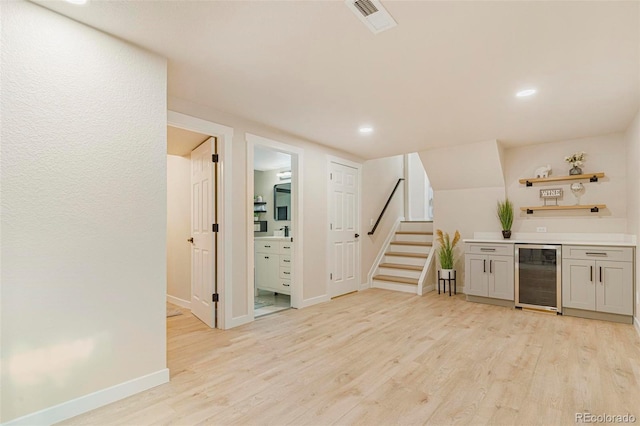 bar featuring light hardwood / wood-style floors, white cabinetry, and beverage cooler