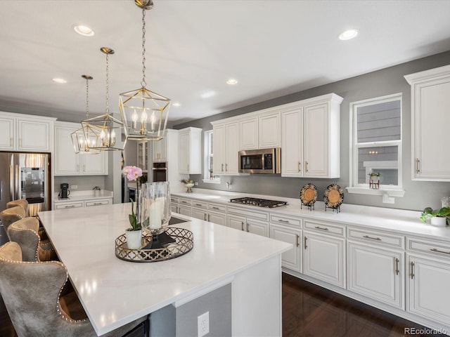 13041 Reata Ridge Dr, Parker, CO 80134 - kitchen with white cabinets, an inviting chandelier, a center island, stainless steel appliances, and a kitchen bar