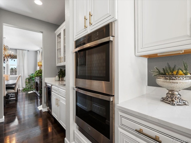 13041 Reata Ridge Dr, Parker, CO 80134 - kitchen featuring double oven, beverage cooler, dark wood-style floors, light countertops, and white cabinets
