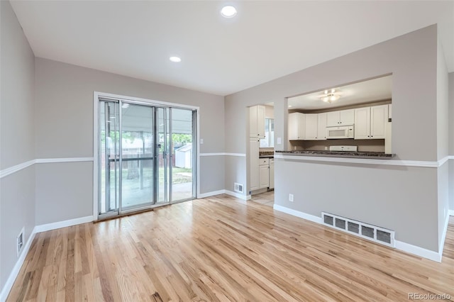 interior space with white cabinetry and light hardwood / wood-style flooring