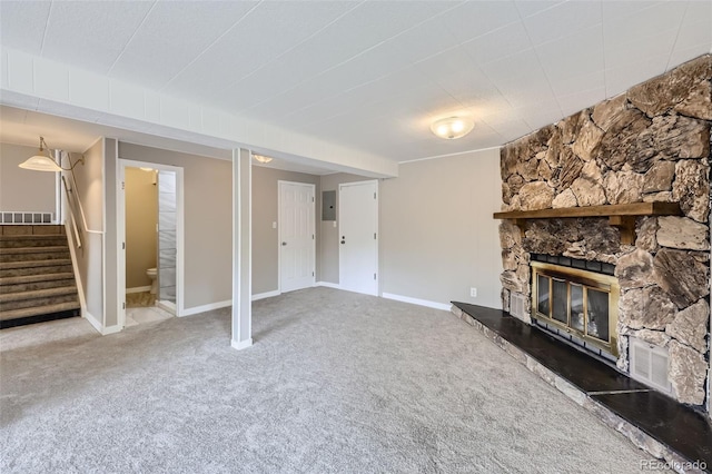 unfurnished living room with a stone fireplace, carpet floors, and electric panel