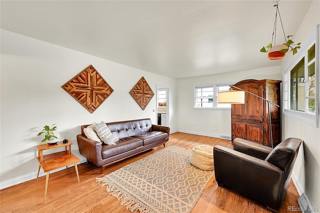 living area with a baseboard radiator, baseboards, and light wood-style floors
