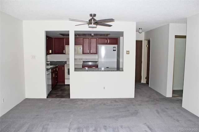 kitchen featuring a textured ceiling, ceiling fan, dark carpet, and white appliances