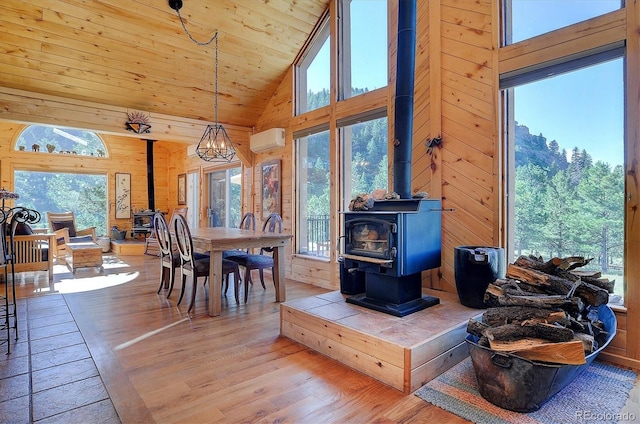 dining room featuring a wood stove, high vaulted ceiling, and an inviting chandelier