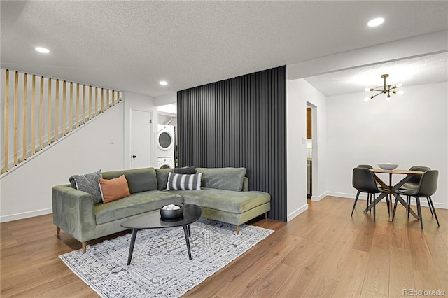 7995 E Mississippi Ave Unit K3, Denver, CO 80247 - living area with stacked washer and clothes dryer, light wood-style flooring, a textured ceiling, stairs, and a chandelier