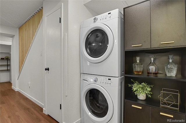 7995 E Mississippi Ave Unit K3, Denver, CO 80247 - laundry area with stacked washer and clothes dryer, wood finished floors, and cabinet space