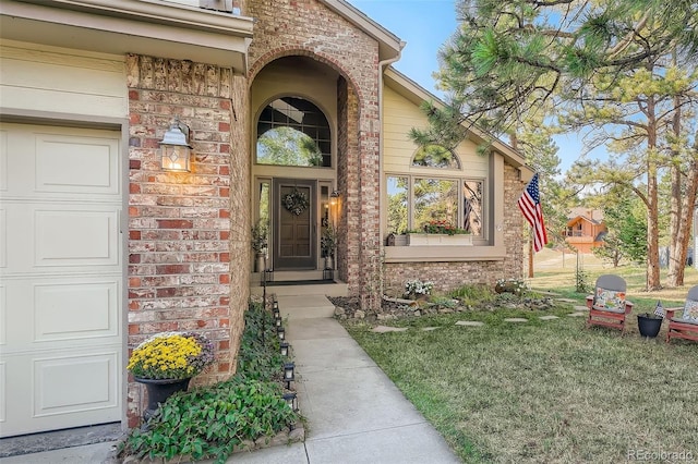 property entrance with a garage, a yard, and brick siding