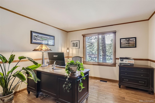 office space featuring baseboards, light wood finished floors, visible vents, and crown molding