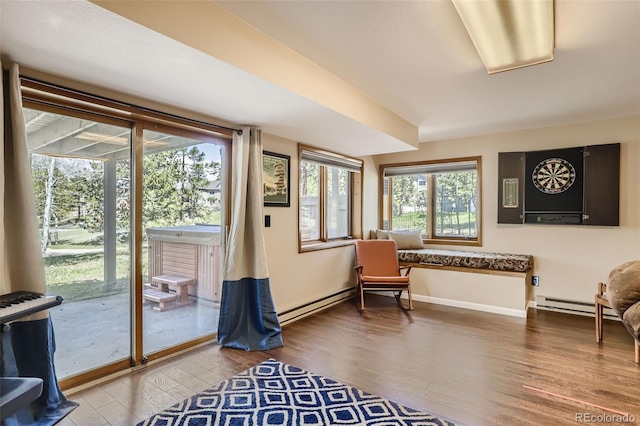 living area featuring a baseboard radiator, baseboards, and wood finished floors