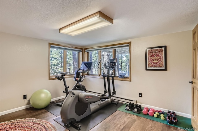 workout room with a textured ceiling, wood finished floors, and baseboards