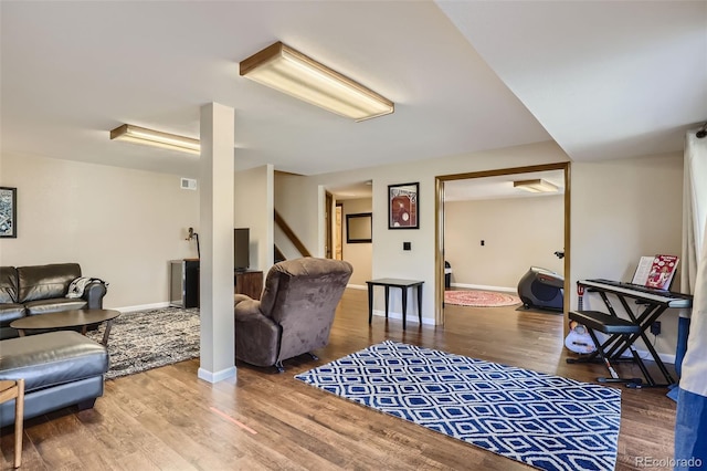 living room featuring visible vents, baseboards, and wood finished floors