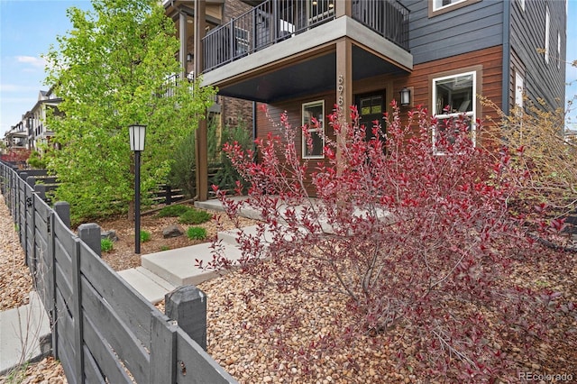 exterior space featuring covered porch, fence, and a balcony