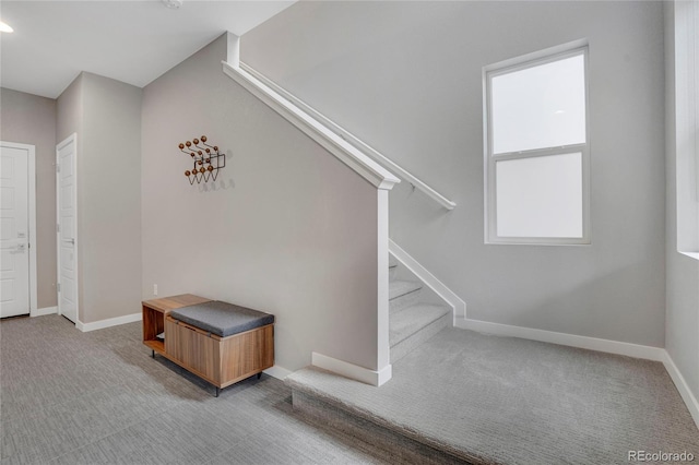 interior space featuring baseboards, carpet, stairs, and a wealth of natural light