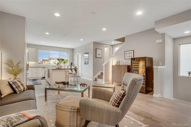 living room featuring recessed lighting, baseboards, light wood finished floors, and stairs