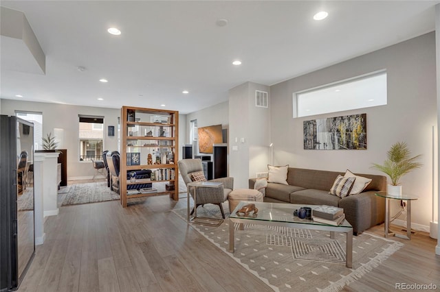 living area with recessed lighting, baseboards, visible vents, and wood finished floors