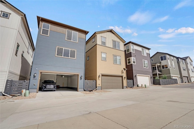 back of property with a residential view, an attached garage, and driveway