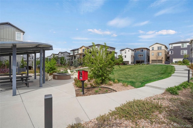 view of property's community with a yard, a patio, a residential view, and an outdoor fire pit