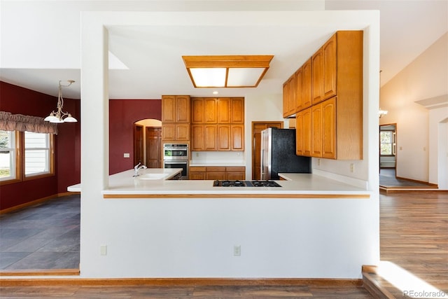 6668 Fairways Dr, Longmont, CO 80503 - kitchen with stainless steel appliances, a sink, light countertops, brown cabinets, and arched walkways
