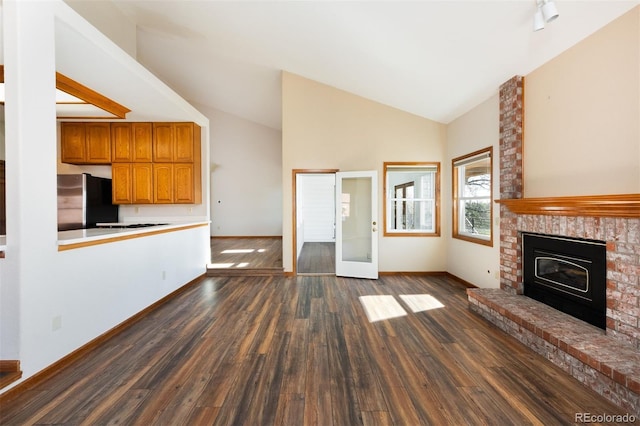 6668 Fairways Dr, Longmont, CO 80503 - unfurnished living room with dark wood-style floors, baseboards, a fireplace, french doors, and high vaulted ceiling