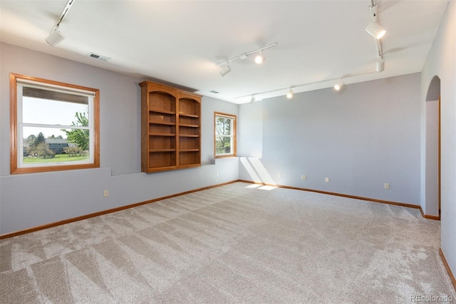 6668 Fairways Dr, Longmont, CO 80503 - spare room with track lighting, carpet flooring, baseboards, and arched walkways
