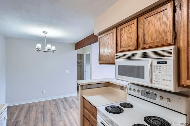 kitchen with white appliances, a chandelier, brown cabinets, a textured ceiling, and light wood-style floors