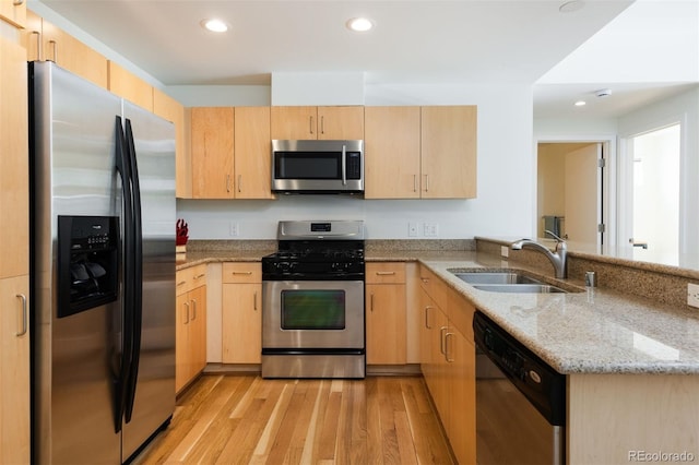 kitchen featuring sink, kitchen peninsula, stainless steel appliances, light stone countertops, and light brown cabinets