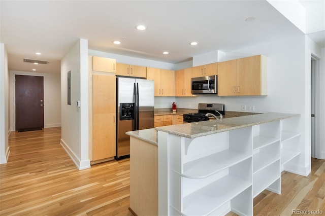 kitchen featuring appliances with stainless steel finishes, kitchen peninsula, light stone countertops, light brown cabinets, and light wood-type flooring