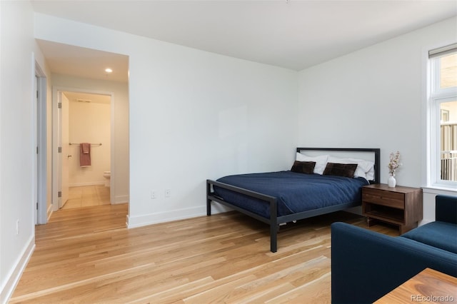 bedroom with ensuite bath and light hardwood / wood-style flooring