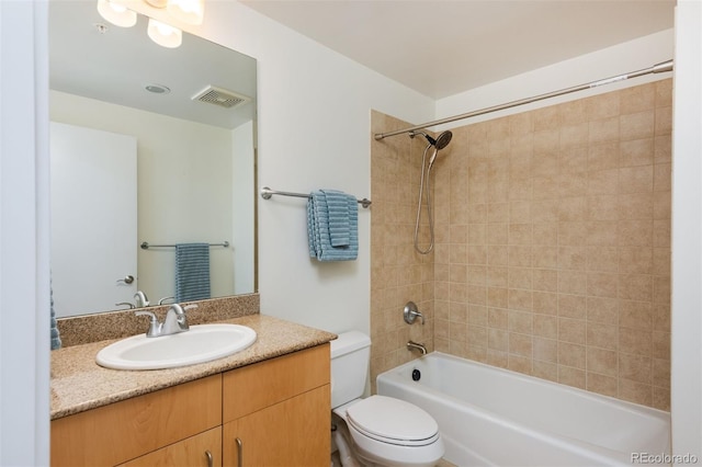 full bathroom featuring tiled shower / bath, vanity, and toilet