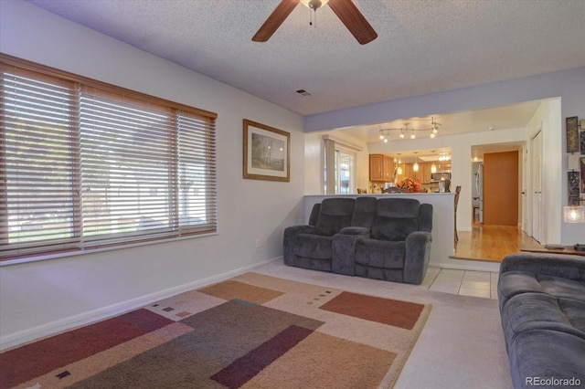 living room featuring light carpet, a textured ceiling, and ceiling fan