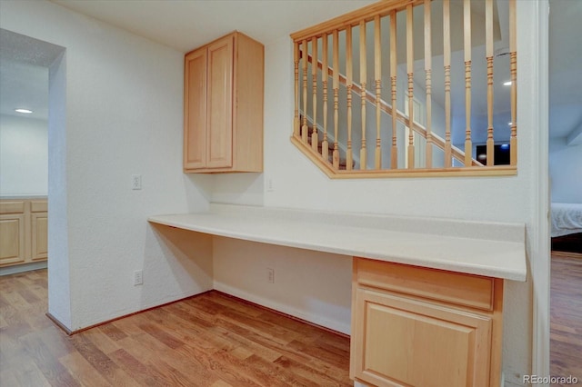 interior space featuring light brown cabinetry, light hardwood / wood-style flooring, and built in desk