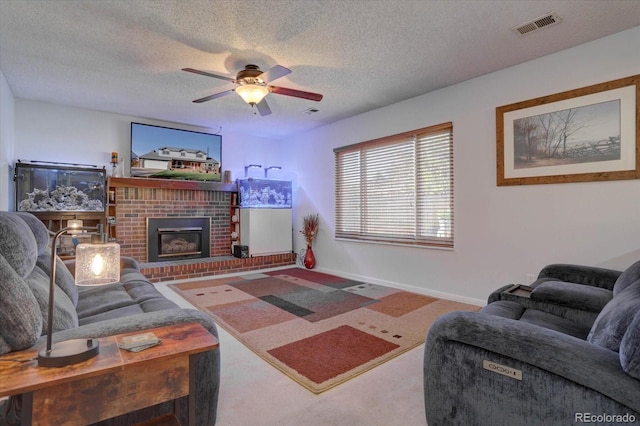 living room featuring ceiling fan, carpet, a textured ceiling, and a brick fireplace