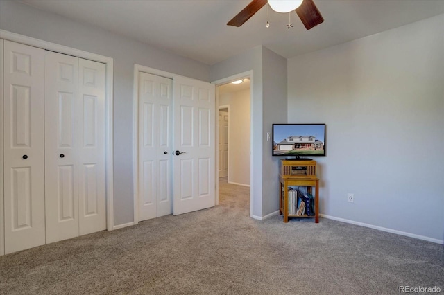 bedroom featuring two closets, ceiling fan, and light colored carpet