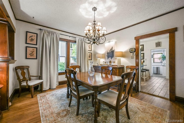 2131 Eliot St, Denver, CO 80211 - dining room with a textured ceiling, a chandelier, wood finished floors, ornamental molding, and baseboards