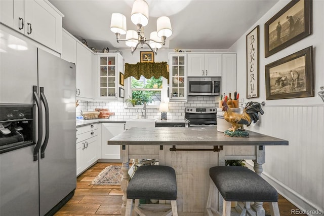 2131 Eliot St, Denver, CO 80211 - kitchen with stainless steel appliances, wood finished floors, a breakfast bar area, decorative backsplash, and white cabinets