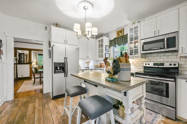 2131 Eliot St, Denver, CO 80211 - kitchen featuring stainless steel appliances, a chandelier, white cabinets, decorative backsplash, and wood finished floors