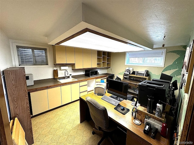 office area with built in desk, a textured ceiling, and sink