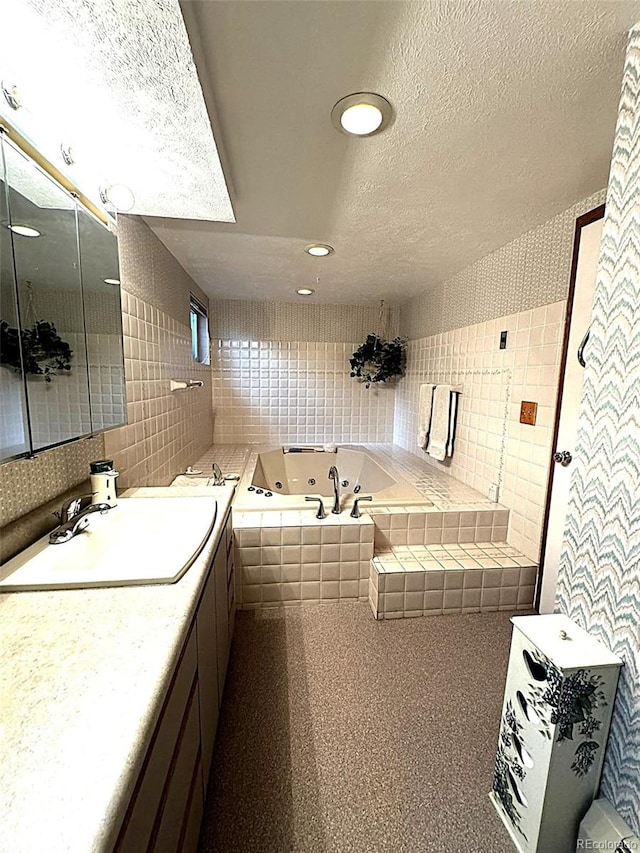 bathroom featuring tile walls, vanity, a textured ceiling, and a relaxing tiled tub