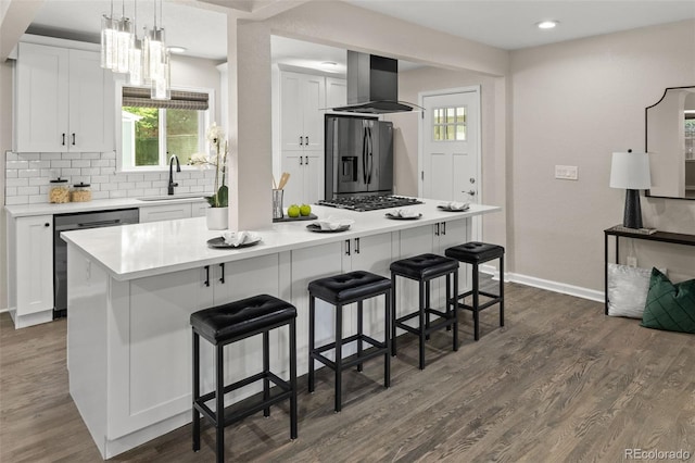 1120 S Harrison St, Denver, CO 80210 - kitchen featuring appliances with stainless steel finishes, wall chimney exhaust hood, white cabinets, dark wood-style flooring, and recessed lighting