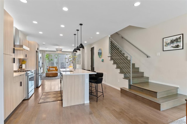 3885 Vrain St, Denver, CO 80212 - kitchen featuring modern cabinets, appliances with stainless steel finishes, wall chimney range hood, a center island with sink, and light countertops