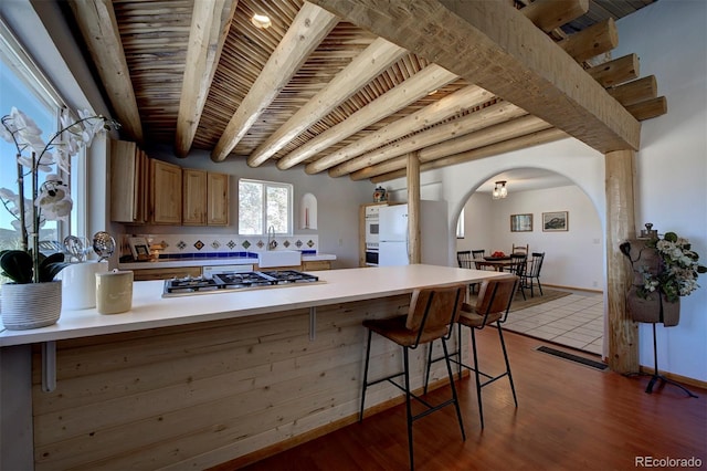 kitchen featuring arched walkways, stainless steel gas cooktop, a peninsula, wood ceiling, and white fridge